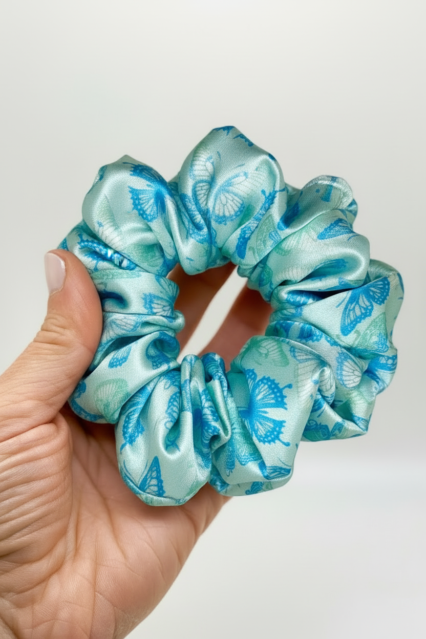 Hand holding turquoise butterfly scrunchie with improved lighting